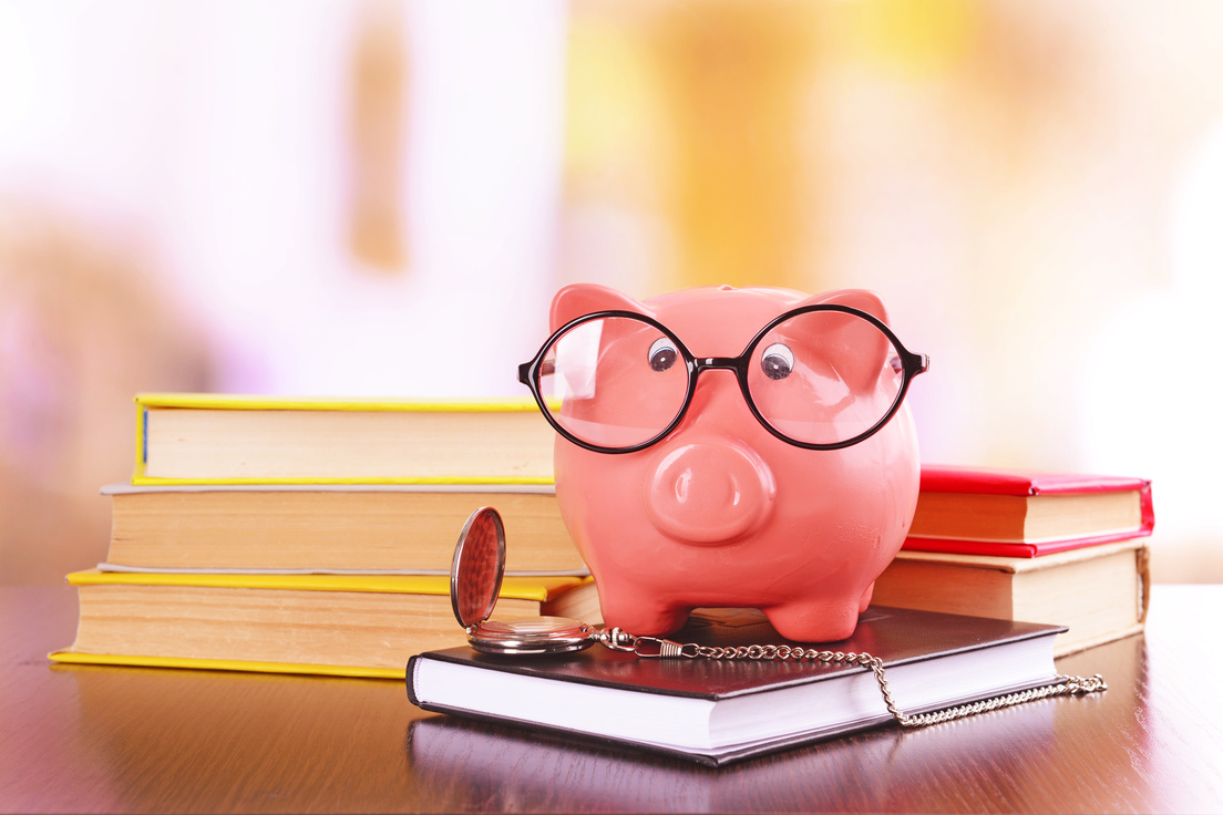 Financial Literacy Concept with Piggy Bank, Eyeglasses, Pocketwatch, and Books